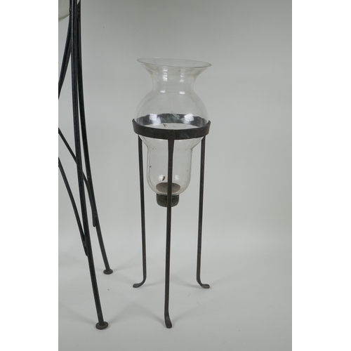 123 - A glass hurricane vase on a wrought iron stand, and another, largest 76cm high