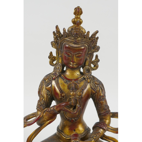 145 - A Tibetan gilt bronzed metal figure of Buddha holding a vajra, 21cm high