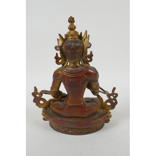 145 - A Tibetan gilt bronzed metal figure of Buddha holding a vajra, 21cm high