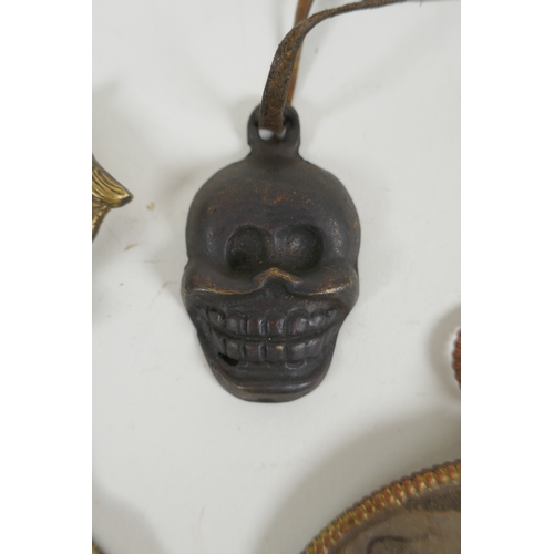 146 - A Tibetan metal calendar, a convex mirror pendant and a cast iron skull pendant, 10cm diameter