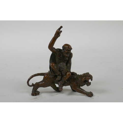 197 - A Chinese bronze figure of Lohan riding a tiger, 7cm long