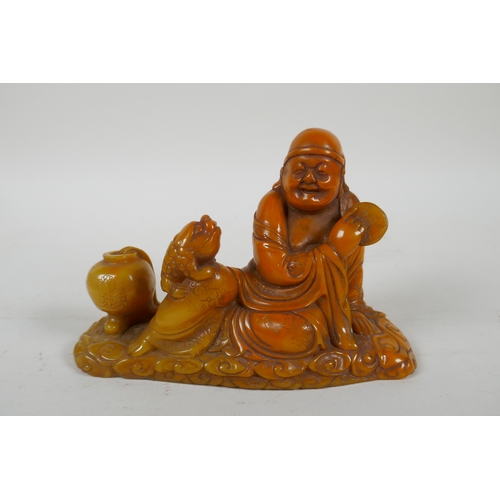 215 - A Chinese imitation amber soapstone carving of Lohan, the base carved for seal, 16cm long