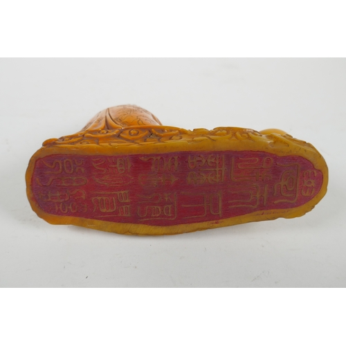 215 - A Chinese imitation amber soapstone carving of Lohan, the base carved for seal, 16cm long