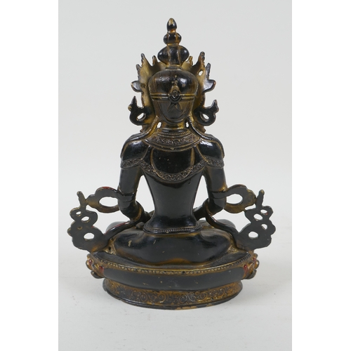 221 - A Tibetan lacquered and gilt bronze Buddha holding a stupa, 22cm high