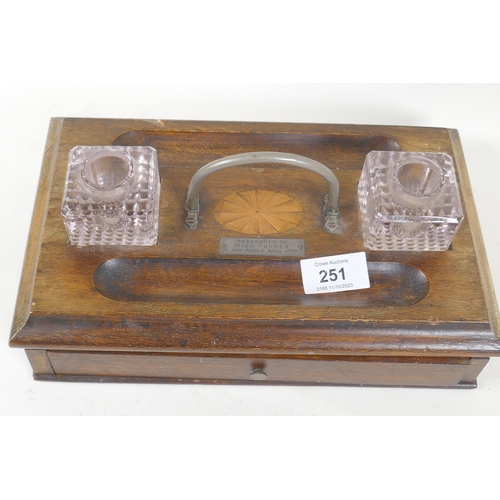 251 - A mahogany desk stand with two glass inkwells and inlaid decoration, bears plaque, present to Miss T... 