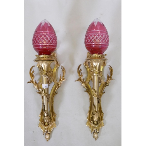 289 - A pair of ormolu wall sconces of trumpet form with leaf swags and cranberry glass shades, 63cm high