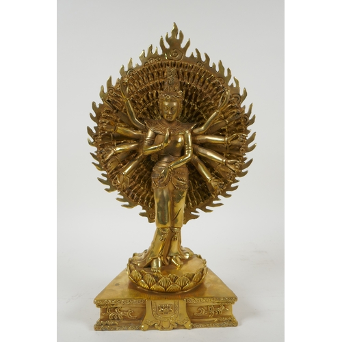 40 - A Tibetan gilt bronze figure of a many armed deity standing on a lotus flower, 32cm high