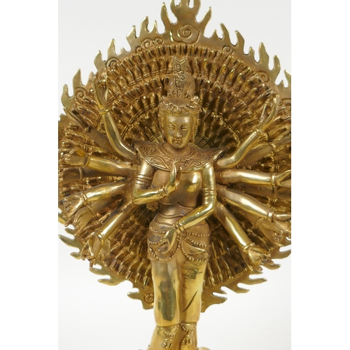 40 - A Tibetan gilt bronze figure of a many armed deity standing on a lotus flower, 32cm high