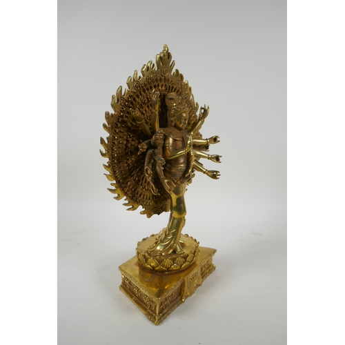 40 - A Tibetan gilt bronze figure of a many armed deity standing on a lotus flower, 32cm high