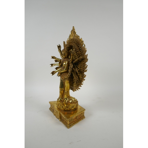 40 - A Tibetan gilt bronze figure of a many armed deity standing on a lotus flower, 32cm high