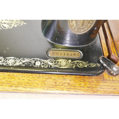 84 - A Singer hand cranked sewing machine, No F6515489, in an oak case