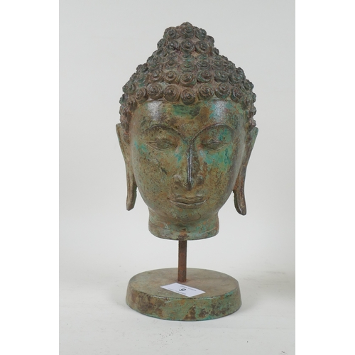 9 - A vintage bronze Buddha's head with green patination, mounted on a stand, 27cm