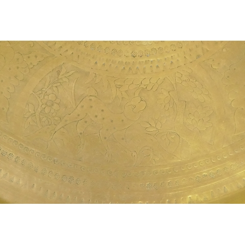 90 - An Islamic brass tray with script decoration, together with another larger decorated with Islamic sc... 