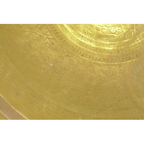 90 - An Islamic brass tray with script decoration, together with another larger decorated with Islamic sc... 