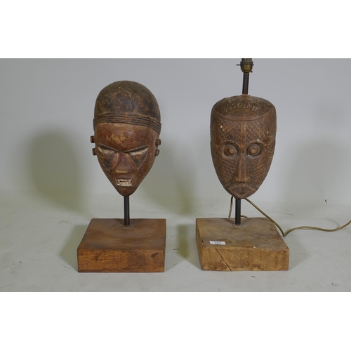 104 - Two antique African painted and carved wood masks, partially converted to lamps, 53cm high