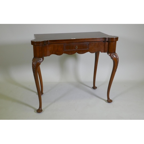 1067 - A George style walnut card table with shaped top and frieze, fitted with a single drawer, raised on ... 