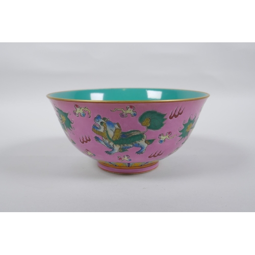 112 - A Chinese polychrome porcelain rice bowl, decorated with temple lions on a pink field, inscription t... 