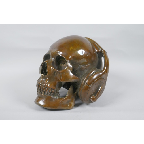 126 - A decorative filled bronze skull wearing headphones, 16cm high