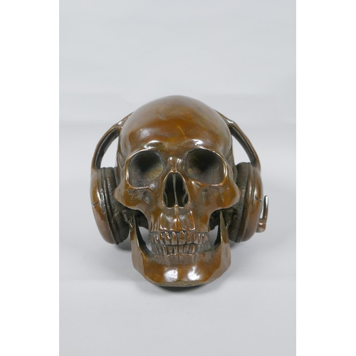 126 - A decorative filled bronze skull wearing headphones, 16cm high