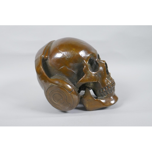 126 - A decorative filled bronze skull wearing headphones, 16cm high