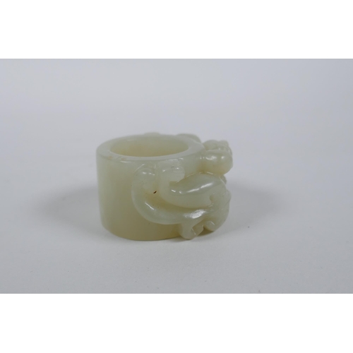 135 - A Chinese grey jade archer's thumb ring with carved dragon decoration, 4.5cm diameter