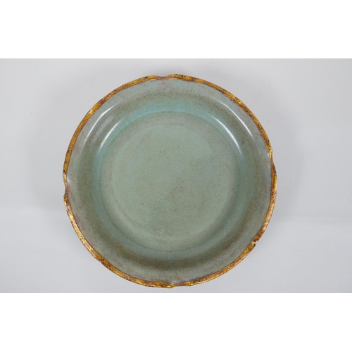 137 - A Chinese celadon glazed porcelain dish with gilt metal lobed rim, chased and gilt character inscrip... 