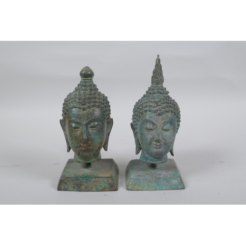 147 - A pair of bronze Buddha's heads with green patina, mounted on a metal stand, 16cm high