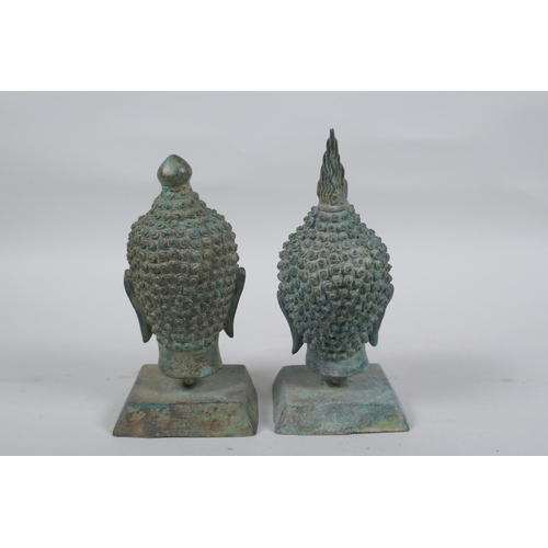 147 - A pair of bronze Buddha's heads with green patina, mounted on a metal stand, 16cm high