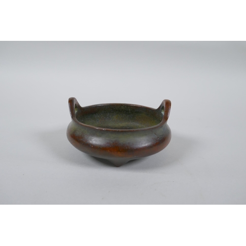 173 - A Chinese bronze censer with two phoenix eye handles and tripod supports, impressed seal mark to bas... 