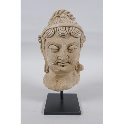 174 - A Gandahar style plaster bust, on a display stand, 18cm high