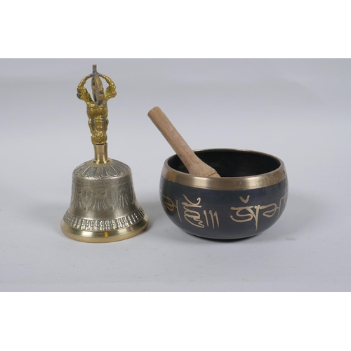 183 - A Tibetan bronze singing bowl with script decoration and wood beater, and a brass ceremonial bell wi... 