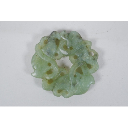 188 - A Chinese carved and pierced mottled green jade pendant with entwined carp decoration, 6cm diameter