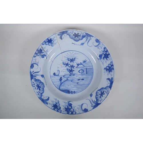 222 - A C19th Delft blue and white tin glazed charger decorated with a riverside landscape, AF, 37cm diame... 