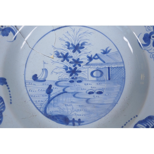 222 - A C19th Delft blue and white tin glazed charger decorated with a riverside landscape, AF, 37cm diame... 