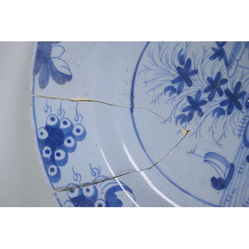 222 - A C19th Delft blue and white tin glazed charger decorated with a riverside landscape, AF, 37cm diame... 