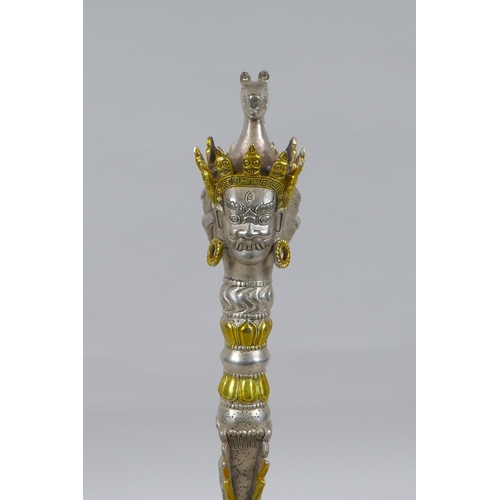 228 - A Tibetan ceremonial metal phurba and stand with gilt metal highlights and wrathful deity masks to h... 