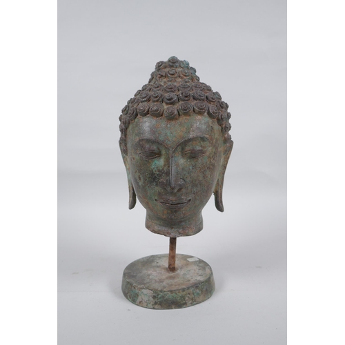 231 - A bronze Buddha head bust on a metal base, with green patina, 26cm high