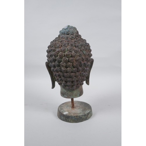 231 - A bronze Buddha head bust on a metal base, with green patina, 26cm high