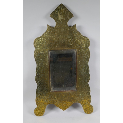 233 - An Islamic brass and hardwood wall mirror with engraved script and scrolling decoration, 33 x 60cm