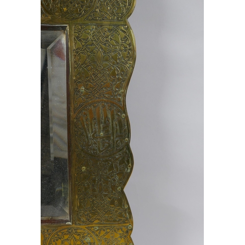 233 - An Islamic brass and hardwood wall mirror with engraved script and scrolling decoration, 33 x 60cm