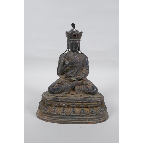 239 - A Sino Tibetan bronze figure of Buddha with the remnants of lacquered patina, 25cm high