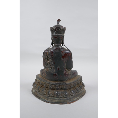 239 - A Sino Tibetan bronze figure of Buddha with the remnants of lacquered patina, 25cm high