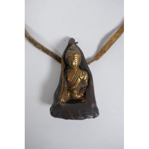 244 - An antique Tibetan bronze Buddha amulet in a leather sheath, 5cm