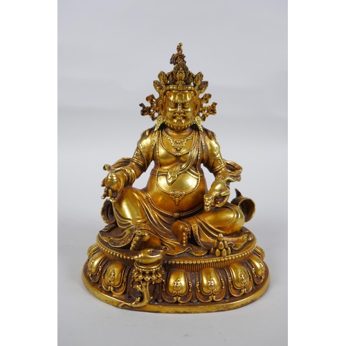 25 - An antique Sino Tibetan heavy gilt bronze figure of Jambhala seated on a lotus throne, double vajra ... 