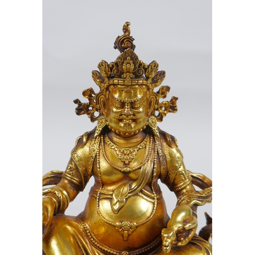 25 - An antique Sino Tibetan heavy gilt bronze figure of Jambhala seated on a lotus throne, double vajra ... 