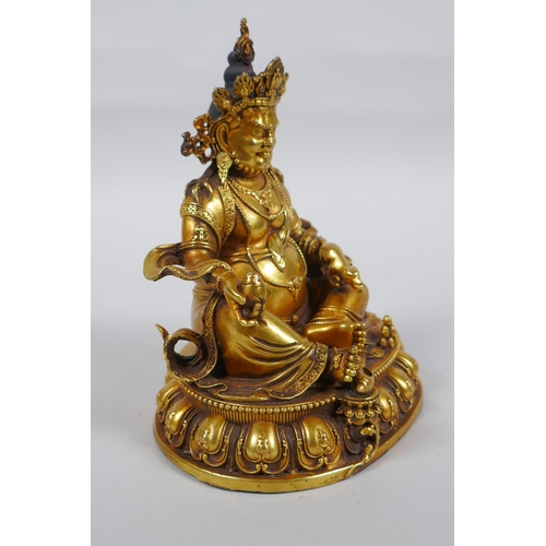 25 - An antique Sino Tibetan heavy gilt bronze figure of Jambhala seated on a lotus throne, double vajra ... 