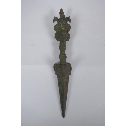 272 - A Tibetan cast iron ceremonial phurba with wrathful deity mask decoration to handle, 32cm long