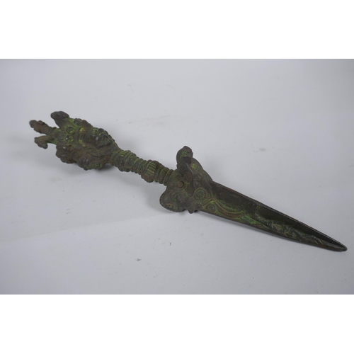 272 - A Tibetan cast iron ceremonial phurba with wrathful deity mask decoration to handle, 32cm long