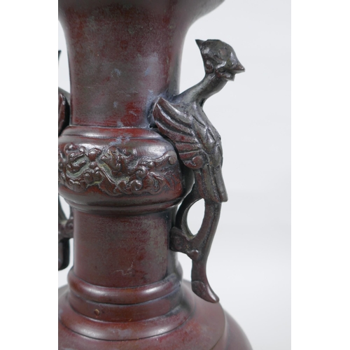 283 - A Chinese bronze vase with two phoenix handles and raised panels depicting dragons, 30cm high