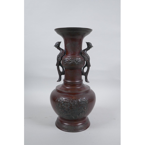 283 - A Chinese bronze vase with two phoenix handles and raised panels depicting dragons, 30cm high